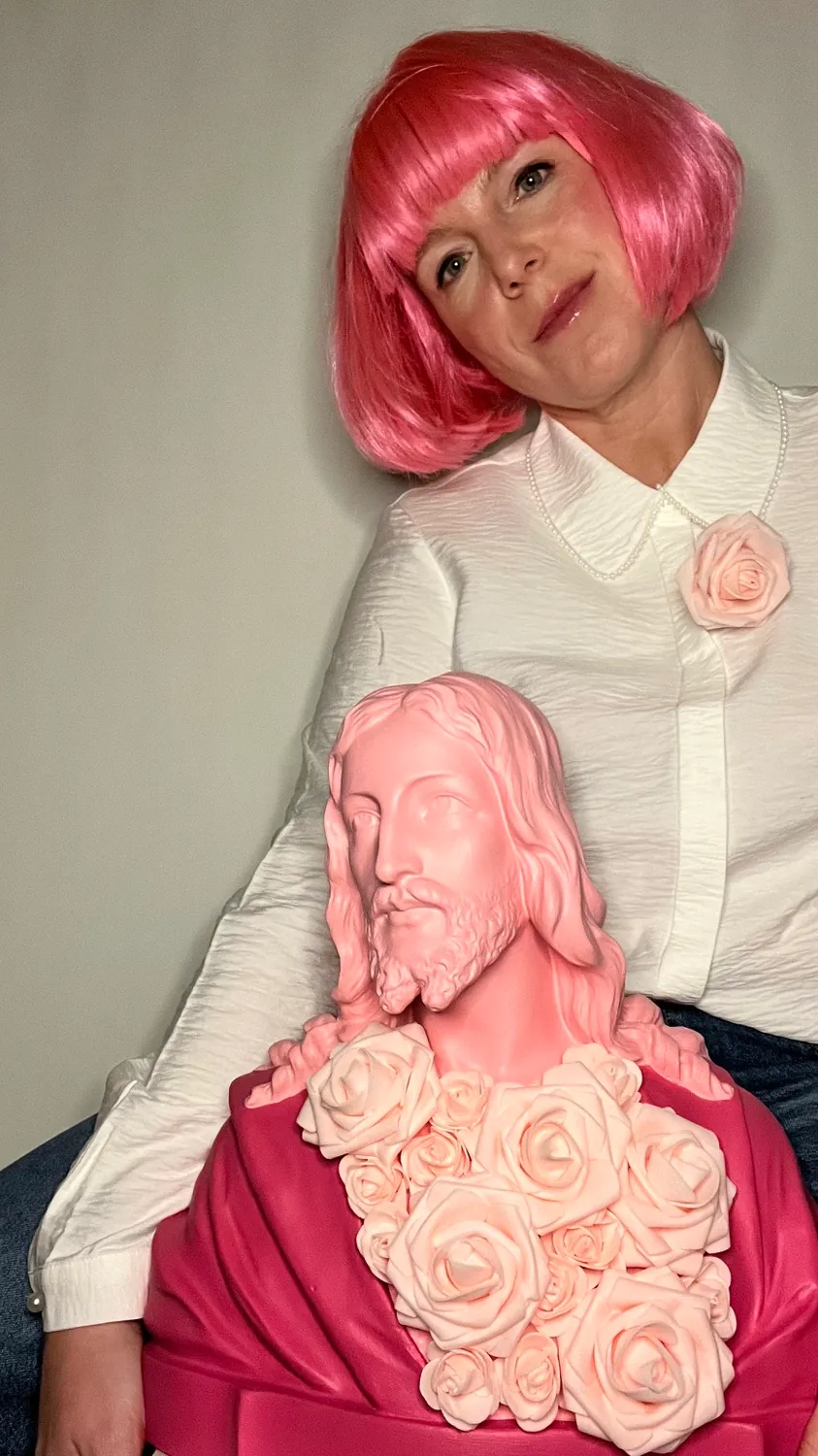 Jill met een roze pruik, een roze Jezusbuste met rozen op schoot